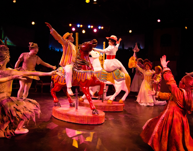 Bert (L- Jeffrey Shankle) and Mary Poppins (R- Maura Hogan) go for a carousel ride in the park during "Jolly Holiday"