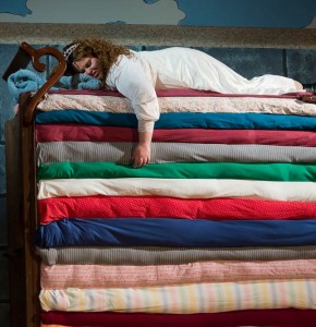 Princess Winnifred (Amy E. Haynes) attempting to sleep atop the 20 mattresses (Conceived by Set Designer Elizabeth Tane Kanner)