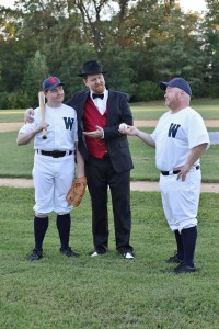 Joe Hardy (L- Jim Gerhardt), Mr. Applegate (C- Ryan Geiger), and Coach Van Buren (R- John Sheldon) discuss a contract