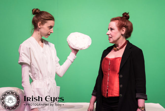 Jacie (Caity Brown), an android performer, prepares to throw a pie at Carla (Diane Sams), the Regional Director.