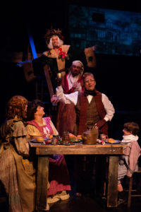 Darren McDonnell (top center) as Ghost of Christmas Present with David Bosley-Reynolds (center) as Ebenezer Scrooge and The Cratchit Family (below, L to R) Katie Tyler as Martha, Tina DeSimone as Mrs. Cratchit, David James as Bob, and Lucas Bromberg as Tiny Tim