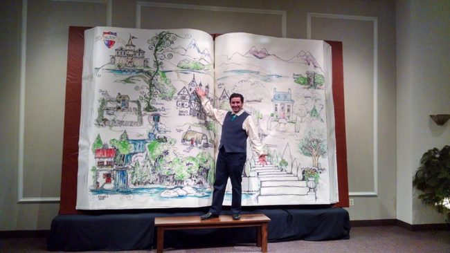 Alexander Foley (as the Mysterious Man) proudly showcases the storybook set piece created by Anne and Greg Foley for Storytellers: A Theater Arts Academy's production of Into the Woods