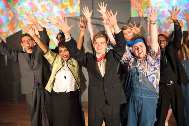 Nick Zuelsdorf (center) as J. Pierrepont Finch and the "Brotherhood of Men" ensemble