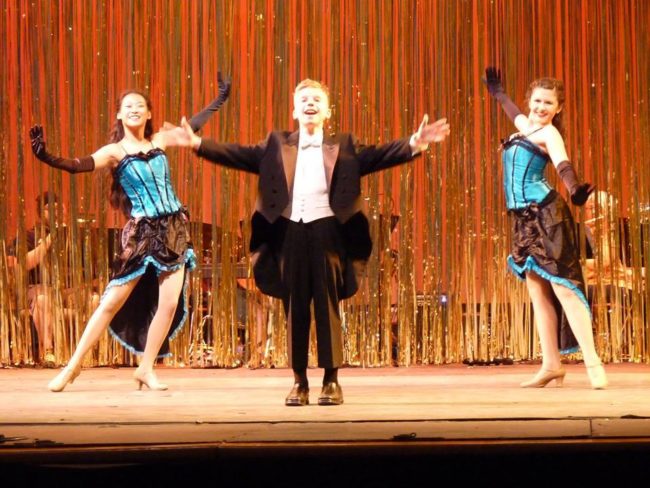 Sammy Jungwirth (featured center) as the Broadway Melody Host in Singin' in the Rain Jr. 