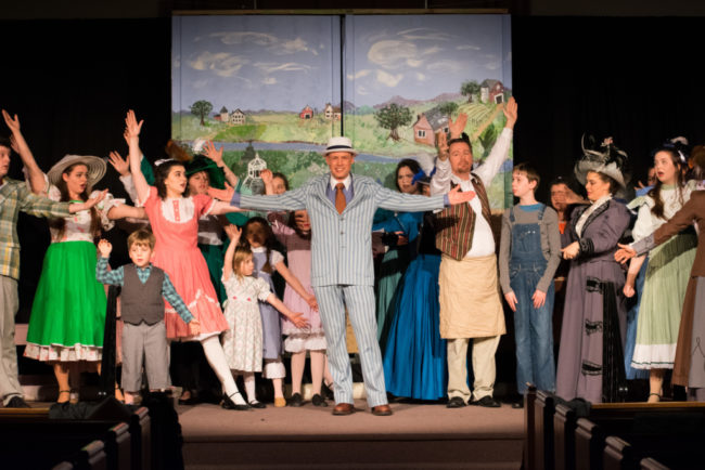 Joe Weinhoffer (center) as Harold Hill and the citizens of River City, Iowa