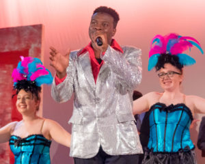 Hosea Mundi (center) as Buddy Rocky and the Showgirls of Honeymoon in Vegas