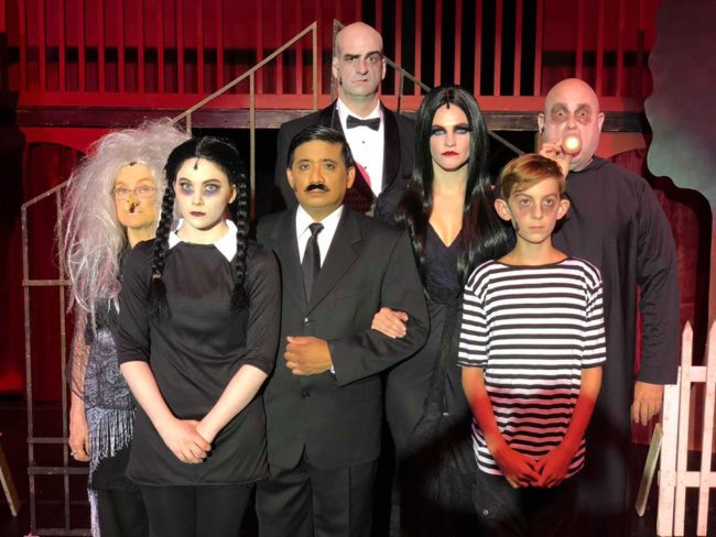 They’re creepy and they’re kooky, mysterious and spooky – and in this case, they’re altogether entertaining! The Addams Family (created by author Charles Addams,) a somewhat unusual clan who were introduced in a comic strip, segued into television in the 1960’s and onto movie screens in the 1990’s have now made their way onto the stage in musical form – and they are just as outrageous as ever. With a stellar cast and brilliant direction by Jonathan C. Jackson, the Tantallon Community Players are bringing highly-energized, Broadway-caliber performances of this 2010 comedy to the Harmony Hall Regional Center in Fort Washington, MD – and from the abundance of laughing, whistling, and cheering heard in the house on opening night, audiences aren’t going to be able to get enough of the quirky tribe – or this phenomenal production. For those not familiar, the Addamses are like any other family… except… not. They prefer the shadier side of life – the more macabre and torturous the better. Smooth-talking Gomez and darkly-sexy Morticia are parents to “goth-before-goth-was-a-thing” daughter Wednesday – and her brother/victim, Pugsley; the odd-but-loveable Uncle Fester – Gomez’s brother – also lives with them, as does apothecary Grandma (though no-one remembers if she is actually related to anyone in the house.) Lurch, their butler, is an ominous figure of few words – well, let’s be honest, he mostly grunts. Cousin Itt, who resembles a mop wearing a hat and glasses, makes a cameo appearance. Then there’s the disembodied hand, called simply, “Thing,” who offers himself when needed (see what I did there?) Oh, yeah, there’s also a group of ghostly Addams ancestors – visible to some, but not all – who lurk about the place randomly bursting into song and dance. Normally, everyone is perfectly unhappy with the status quo – and that is a good thing. However, on this particular occasion, Wednesday would like her family to be a little less like themselves. She’s met a boy – a normal one – and she wants to marry him. But she’s afraid that her family’s… eccentricities, shall we say… might just scare Lucas and his family off. She wants the Addamses to act like “regular” people for once. The question is, are they really capable of that? From the very first moment the cast explodes onto the stage singing, “When You’re an Addams,” it becomes clear you’re in for a treat. The unbelievable spirit built up in the theater is palpable as you watch multiple generations of Addamses, both alive and undead, sing and dance to director Jackson’s wonderfully fluid and sometimes amusingly familiar choreography (there *may* have been some “Thriller” moves thrown into the mix.) As patriarch Gomez Addams, Kieth Flores takes command of a role most famously played by John Astin in the television show and Raul Julia in the movies and easily makes it his own. It may be partially due to the excellent work of costumer Crystal Soul, multiple-hat-wearing Jackson’s wig design, and/or skillful makeup application, but Flores – and truly, each member of the cast – looks like he was born to play his role. Patrick Boyer, in particular, could be the ancestor of Ted Cassidy, who played Lurch in the TV show.  Steve Dasbach is a very sweet and amiable Uncle Fester. When he announces that he’s in love with the moon, you really want it to work out – even if she is a quarter of a million miles away (though he doesn’t mind; he claims that's a good distance for romance.) Spunky Lani Novak takes on the role of Grandma Addams and makes it larger than life. The youngest member of the cast, Jackson Parlante, as Pugsley Addams, embodies the term, “good things come in small packages.” Not only is he a wonderful actor, when he sings his solo, “What If,” it will bring you to tears.  Being on stage with such flamboyant characters can make it difficult for actors with more subdued roles to stand out, but Will Hooper, Libby Dasbach and George Willis as Wednesday’s betrothed and his mother and father, respectively, are to be commended for their fine work in that regard. Dasbach, especially, is hilarious when she accidentally drinks one of Grandma’s potions and really lets her hair down. The talented Nina Jankowicz plays Morticia Adams to sultry perfection and has one of the best singing voices in the cast. However, the true standout in this production is Jayne Saxon Zirkle as Wednesday Addams. Not only does she give her role a lot of layers (which can be difficult to do with a somewhat one-sided character like Wednesday,) she has a killer singing voice – strong, clear and full of emotion. She honestly blew me away. Every aspect of this production is well thought-out and brilliantly executed. There are a lot of small touches that make it special. For instance, at the very top of the show a (presumably battery-run) hand (the aforementioned Thing) rapidly and amusingly skitters across the stage, setting a whimsical tone for the rest of the evening. Lighting designer Levante Evans is to be commended for using spotlights as a masking device while sets are being changed in the background – and for making sure that each and every actor finds his or her light, even if the light has to find them.  So… what are you waiting for? Go see The Addams Family. What’s the magic word, you ask? NOW. Running Time: Approximately 2 hours and 30 minutes with one intermission The Addams Family plays through September 30, 2018 with the Tantallon Community Players at The Harmony Hall Regional Center— 10701 Livingston Road in Fort Washington, MD. Tickets are available at the door or in advance online.