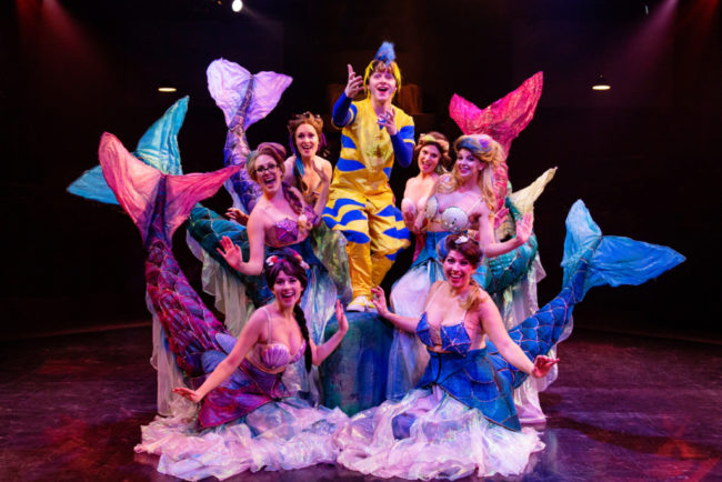Jacob Hale (center) as Flounder with The Mersisters: (from bottom left moving clockwise) Louisa Tringali as Allana, Maggie Dransfield as Andrina, Elizabeth Rayca as Aquata, MaryKate Brouillet as Atina, Rachel Kemp as Arista, and Coby Kay Callahan as Adella. 