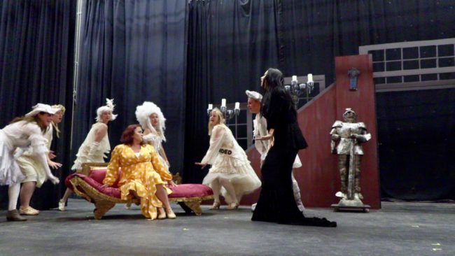 Tiffany Walker Porta Burrows (seated, left) as Alice Beinecke with Michele Guyton (standing, right) as Morticia Addams and The Ancestors. Photo: Tom Littlejohn