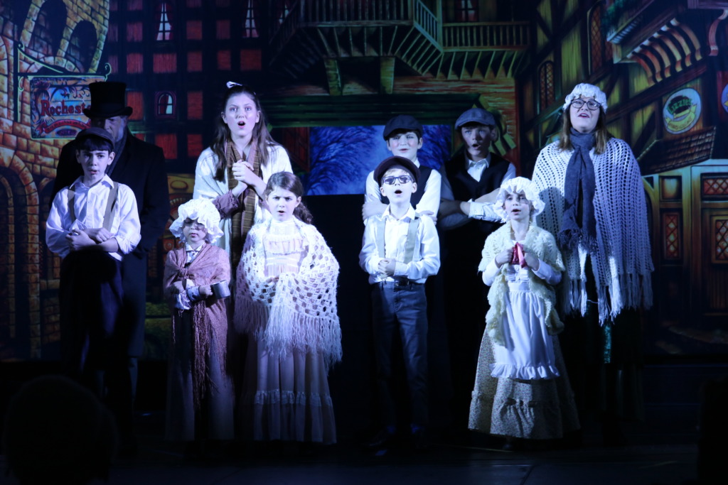 Brett Rohrer (corner back left) as Ebenezer Scrooge and the London Street Carolers. Photo: Kathleen Swain