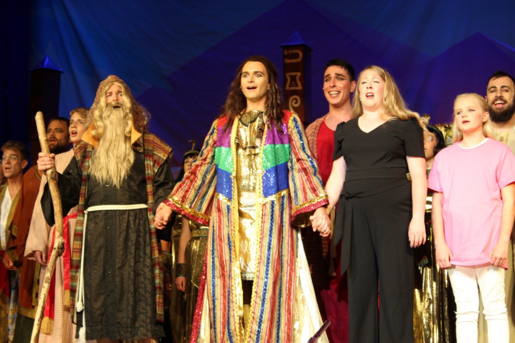 Fr. Gerard Francik (left) as Jacob, with Henry Cyr (center) as Joseph, and Colleen Esposito (right) as Narrator, and the cast of Joseph &... 📸Alison Jones
