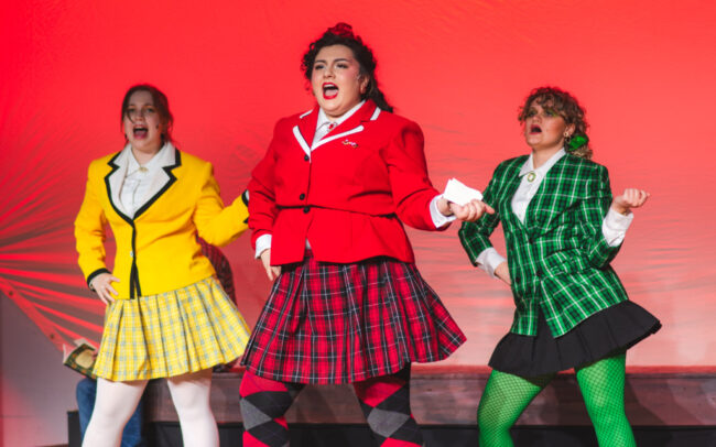 Emily Crawford (yellow) as Heather McNamara, Maddie Saldaña (red) as Heather Chandler, and Sami Peterson (green) as Heather Duke in Heathers at Third Wall Productions 📷 Matthew Peterson
