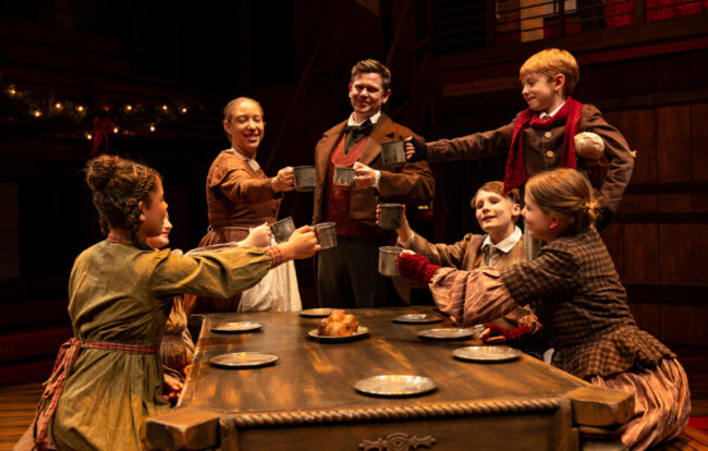 Dawn Thomas Reidy (c-left) and Samuel Richie (c-right) and Cratchit children in Chesapeake Shakespeare Company’s A Christmas Carol 📷Kiirstn Pagan Photography.